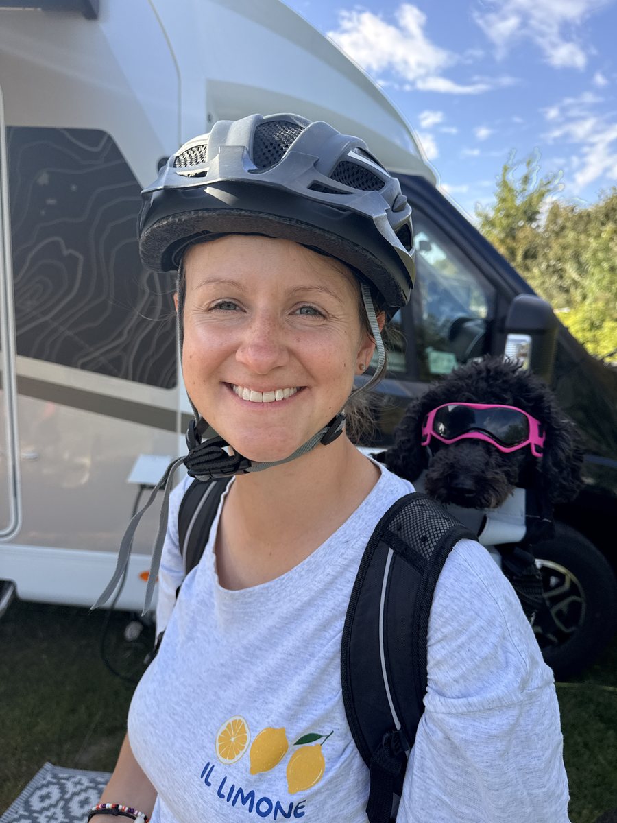 Sarah mit Fahrradhelm, hinter ihr sitzt Pudeldame Amy mit Hundebrille im Rucksack